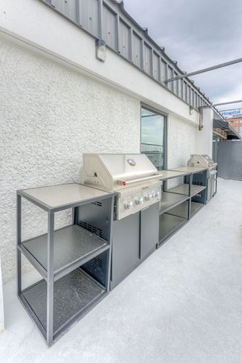 A row of stainless steel grills are lined up on a white wall.